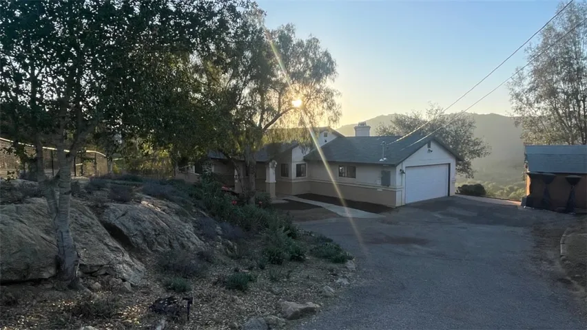 A welcoming first impression with warm light, mature trees, and peaceful hillside surroundings.