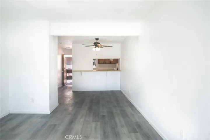 View from the living room, looking towards dining area with ceiling fan, and kitchen that opens up with a convenient pass-through.