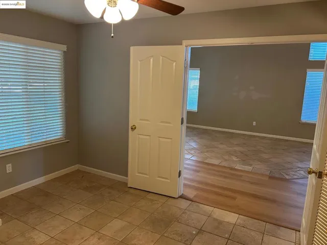 Empty room with light tile patterned flooring and ceiling fan