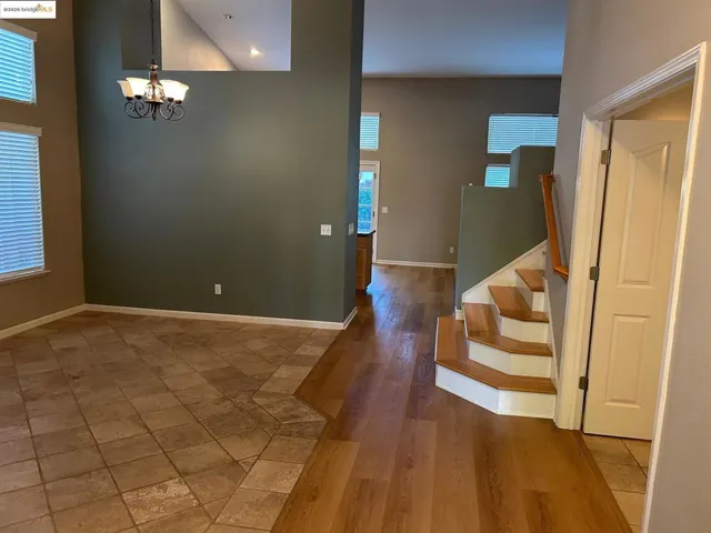 Entryway featuring a high ceiling, stairs, healthy amount of natural light, a chandelier, and wood finished floors