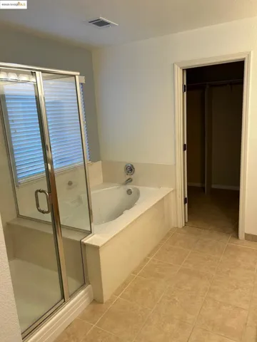 Full bathroom with a bath, a shower stall, light tile patterned floors, and a spacious closet