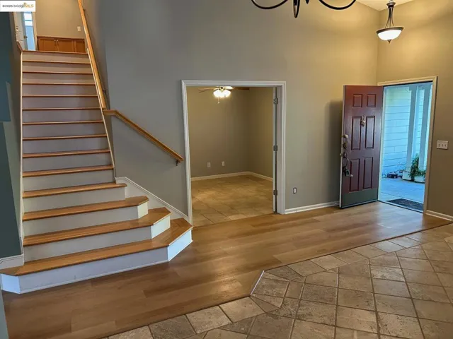 Foyer featuring light wood-type flooring, stairway, a ceiling fan, and a towering ceiling