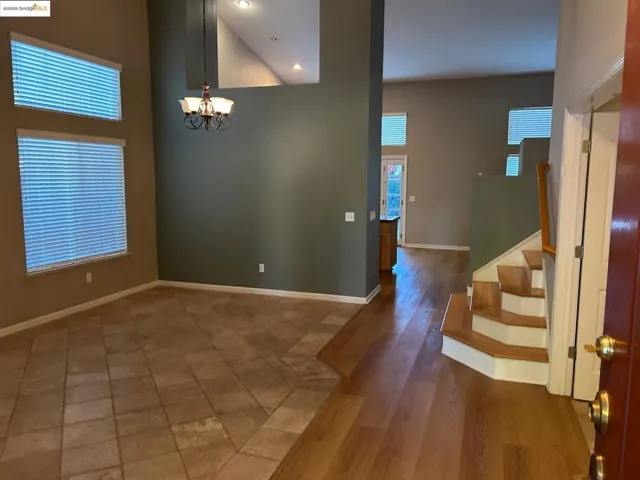 Unfurnished dining area featuring stairs, a high ceiling, a chandelier, dark wood-style floors, and recessed lighting