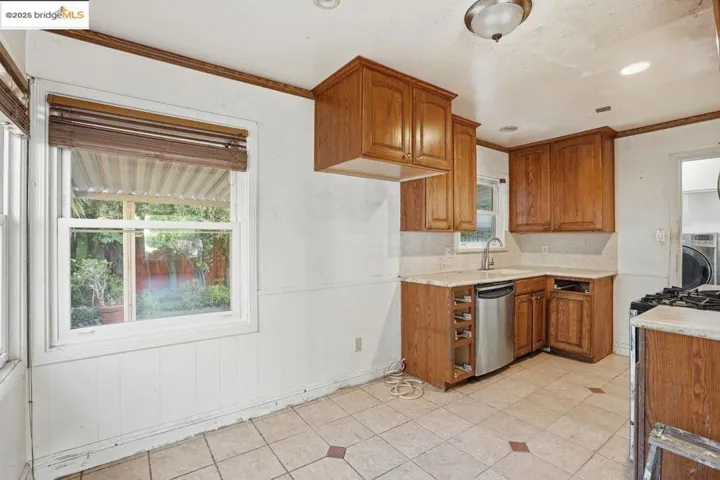 Kitchen with brown cabinetry, stainless steel dishwasher