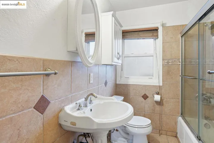 Bathroom featuring enclosed tub / shower combo and tile walls