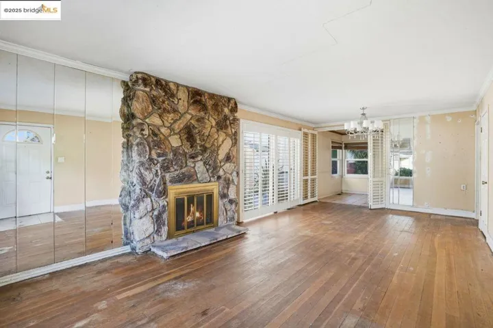 living room with a fireplace, crown molding, a chandelier, and wood-type flooring