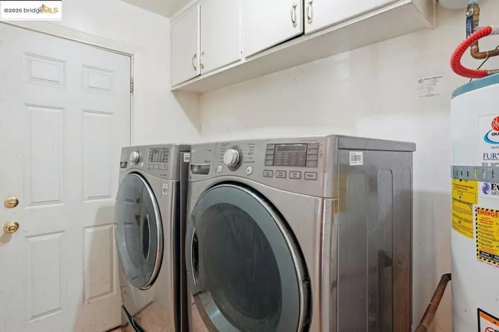 Laundry area featuring  water heater, cabinet space, and washer and dryer