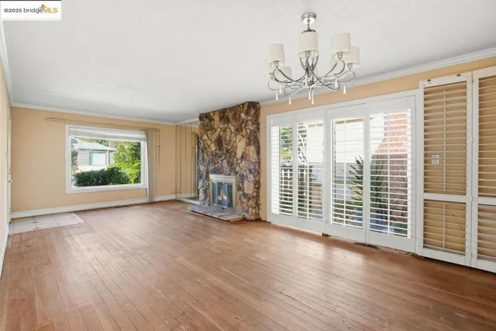 living room  healthy amount of natural light, hardwood / wood-style floors, a stone fireplace, and a chandelier