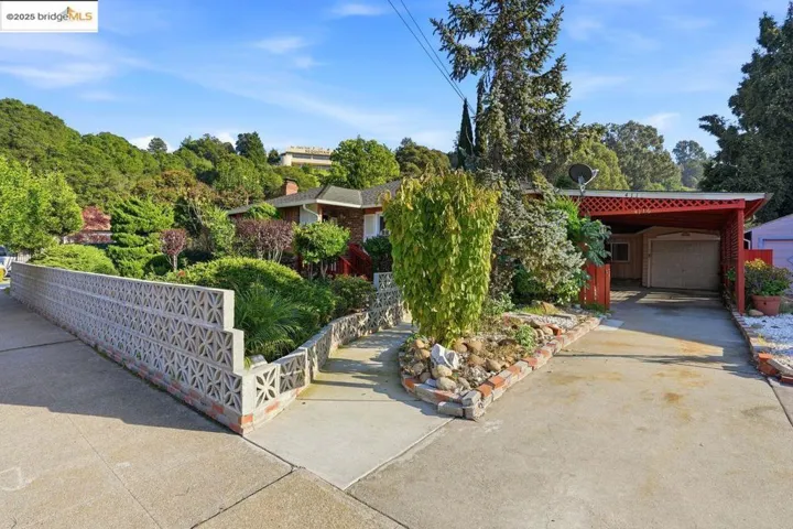 View of property hidden behind natural elements featuring an outdoor structure and concrete driveway