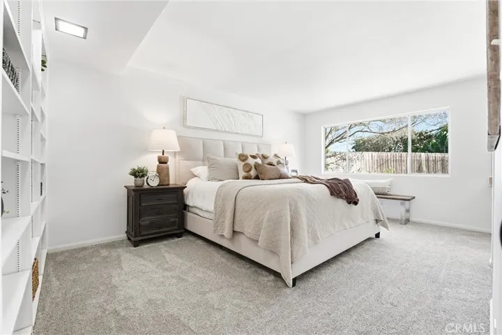Downstairs Primary En Suite with built-in shelving, new carpet and paint, and large window looking into the backyard!