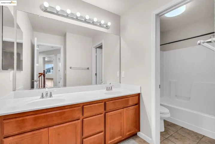Bathroom featuring double vanity, light tile patterned flooring, and bathtub / shower combination