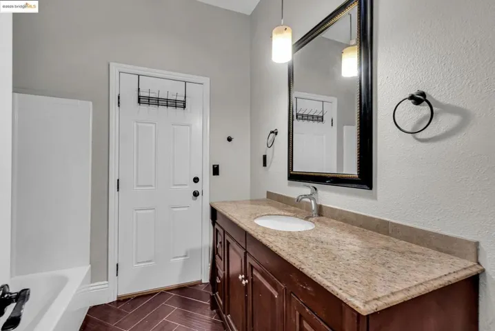 Full bathroom featuring a tub to relax in, vanity, wood tiled floors, and a textured wall