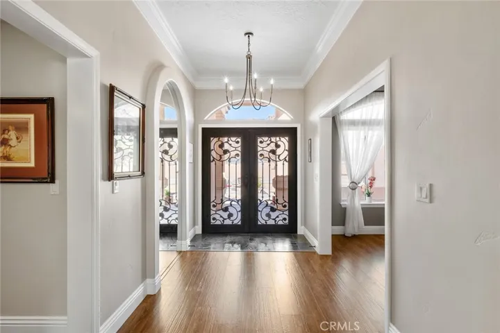 Gorgeous double glass doors accented with intricate rod iron detailing open into an inviting foyer.