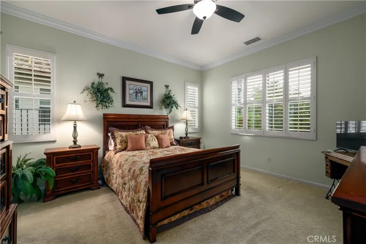 Primary bedroom with crown molding and window shutters.