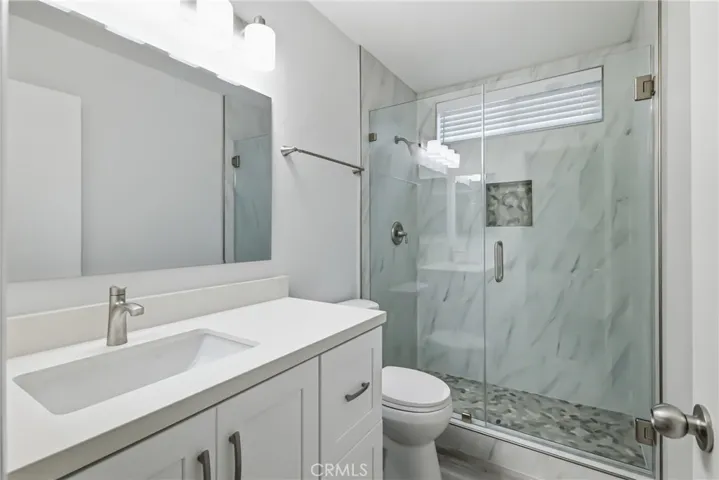 Brand new walk in shower, Vanity, window, blinds, mirror, and floor.