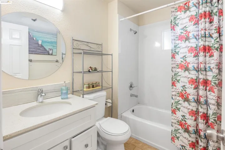 Bathroom with shower / bath combo with shower curtain, vanity, and a textured wall
