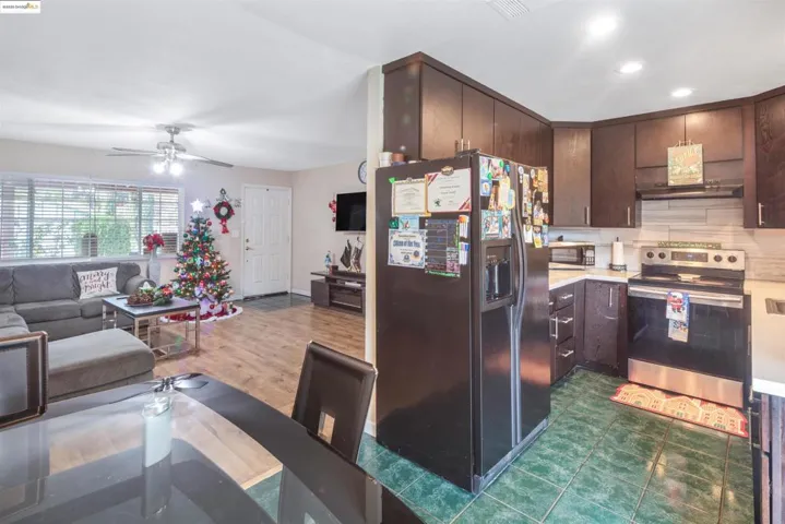 Kitchen with dark brown cabinetry, stainless steel appliances, light countertops, backsplash, and a ceiling fan