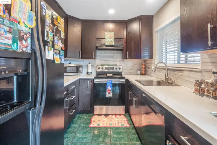 Kitchen featuring black appliances, dark brown cabinetry, backsplash, dark tile patterned flooring, and recessed lighting