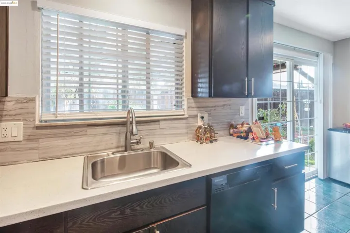 Kitchen with black dishwasher, plenty of natural light, backsplash, and tile patterned flooring