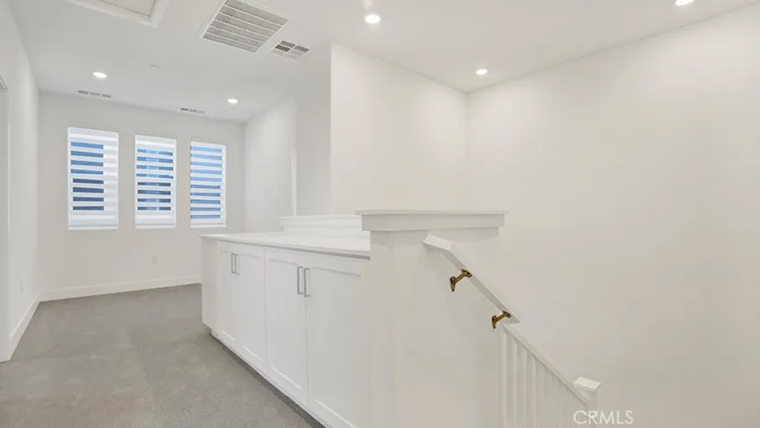 Stairs to upper level to Primary suite and 2 secondary bedrooms.  Notice quartz countertop and cabinets for extra storage.