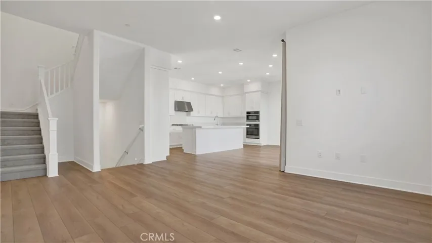 Living area.  Open space, canned in ceiling lighting.  Notice the stairs to the left.  Stairs leading to lower level to front door and 2 car garage.  There are also stairs which are carpeted leading to the 3rd level.