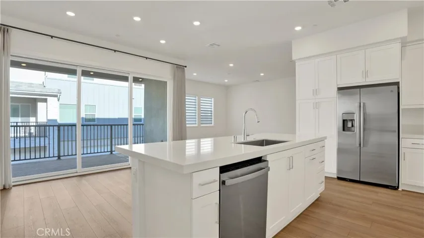 Welcome home.  Living area boasting a beautiful quartz island, wood flooring, sliding glass doors to a outdoor patio.