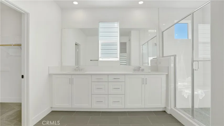 Primary Bathroom with dual sinks, beautiful cabinetry, large shower and natural lighting through the windows.
