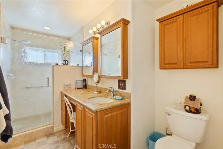 The ensuite bathroom has a generous vanity with quartz countertop and large walk-in shower with decorative rain glass.