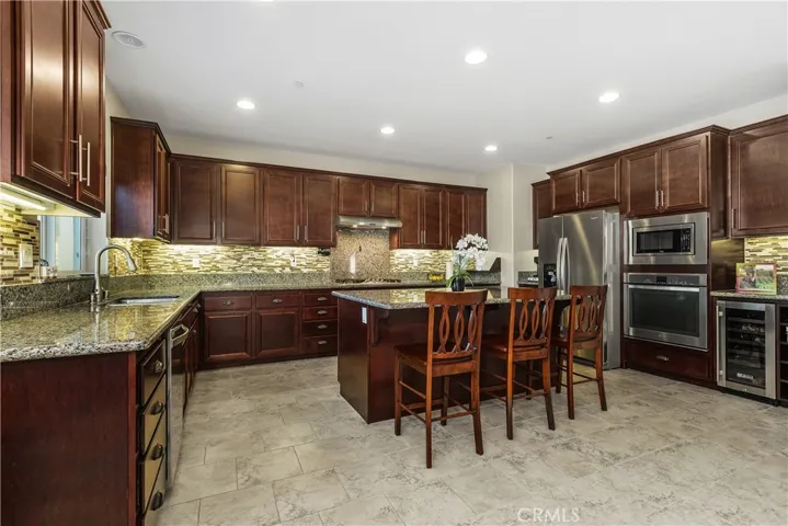 Open kitchen with light granite counters, kitchen island with seating and storage, expresso cabinetry, stainless steel appliances and wine fridge!