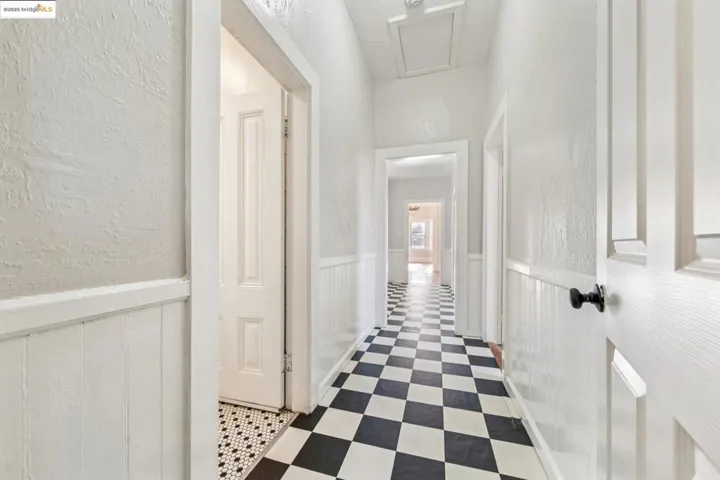 Hall with a textured wall, tile patterned floors, and a wainscoted wall