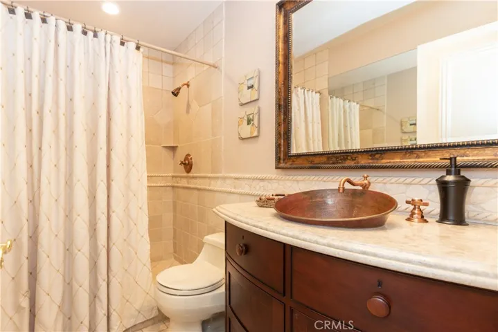 3/4 bath on the main level is upgraded with a vessel sink and vanity, and elegant tilework.