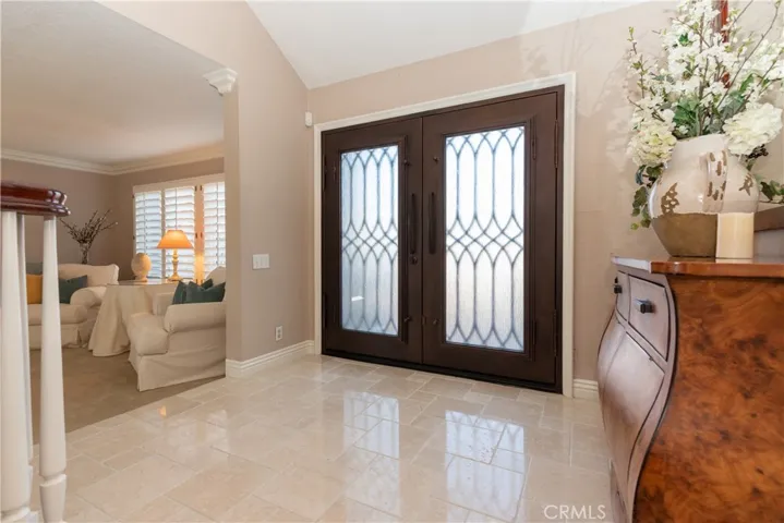 Glass entry doors and stone set travertine foyer.