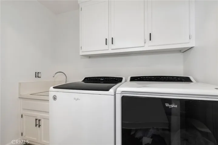 In the hallway you'll find the laundry area complete with sink and cabinets. Bonus, the washer and dryer stay!
