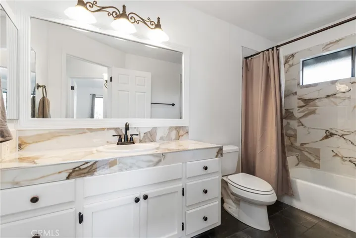 The main bathroom has a stylish atmosphere featuring a generous vanity and tub/shower combination with ceramic tile surround.