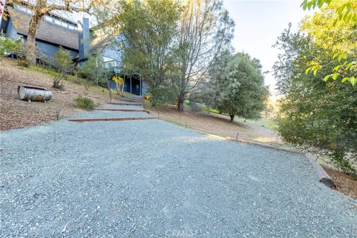 Part way up the driveway is a separate parking area or an area for guests to park for the guest suite. Pathway leads up to the private entrance of the guest suite.