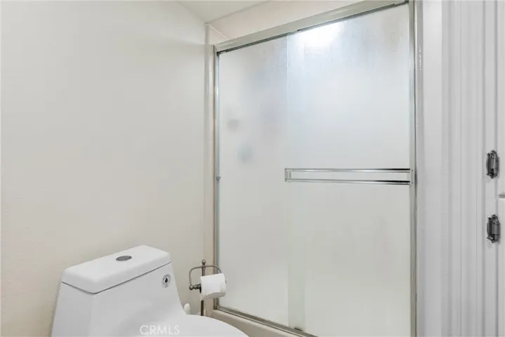 The bathroom has a walk-in shower with privacy glass doors.
