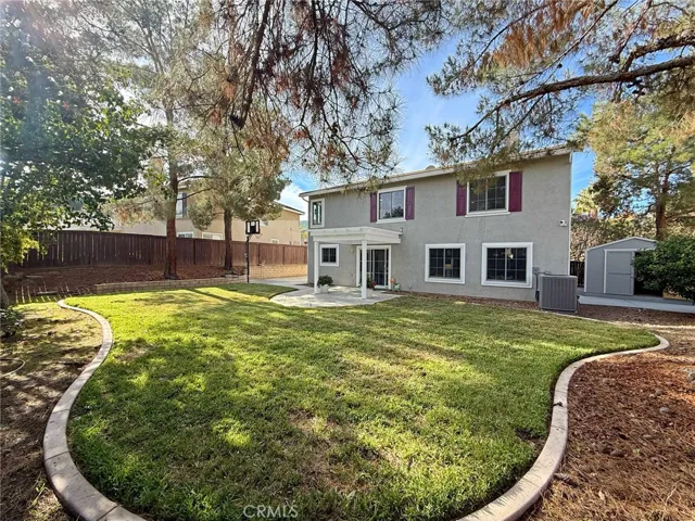 Inviting landscaped backyard featuring a lattice-covered patio and concrete slab, Shed on concrete slab, perfect for outdoor dining, entertaining, or relaxing.