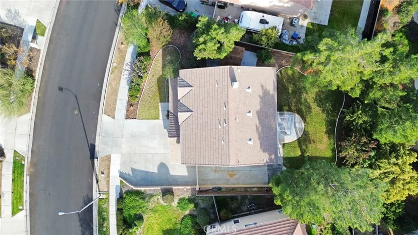 Aerial view of the entire property, highlighting the front yard, driveway, landscaped backyard, patio, and RV slab.