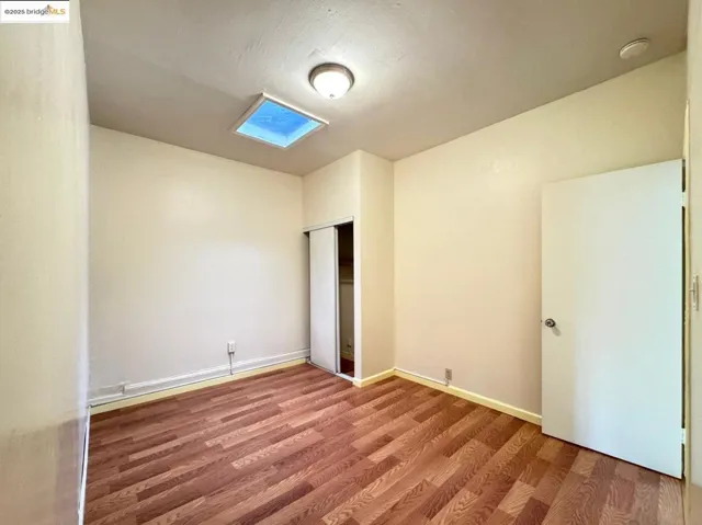 Unfurnished bedroom with wood finished floors and a closet
