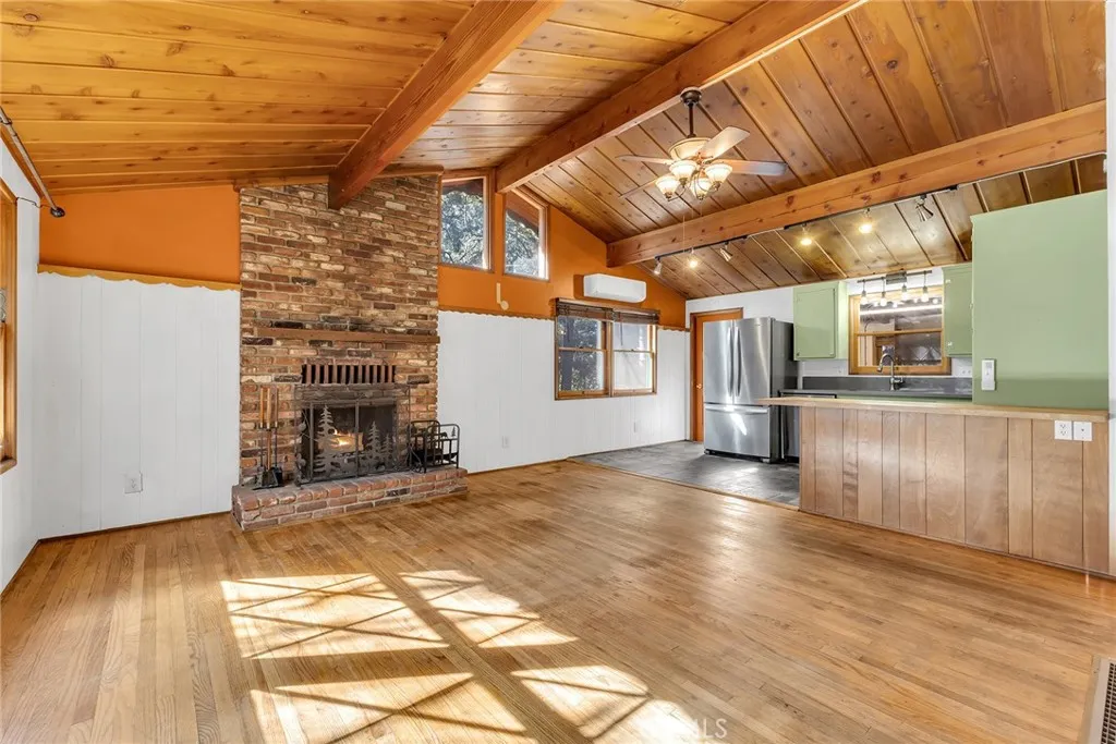 Beautiful living room with wood floor and high  cathedral ceilings with lovely brick fireplace