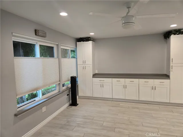 From front door into living room with custom lighting/window shades, flooring and ample built-ins