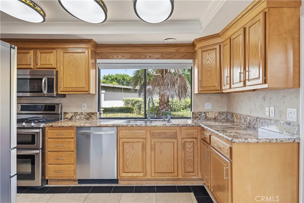 The newly refreshed wooden kitchen cabinets with brand-new handles and window blinds. The window above the kitchen sink showcases beautiful landscaping outside all year long. Granite countertops, and stainless steel appliances with double oven, microwave with unique light fixtures.