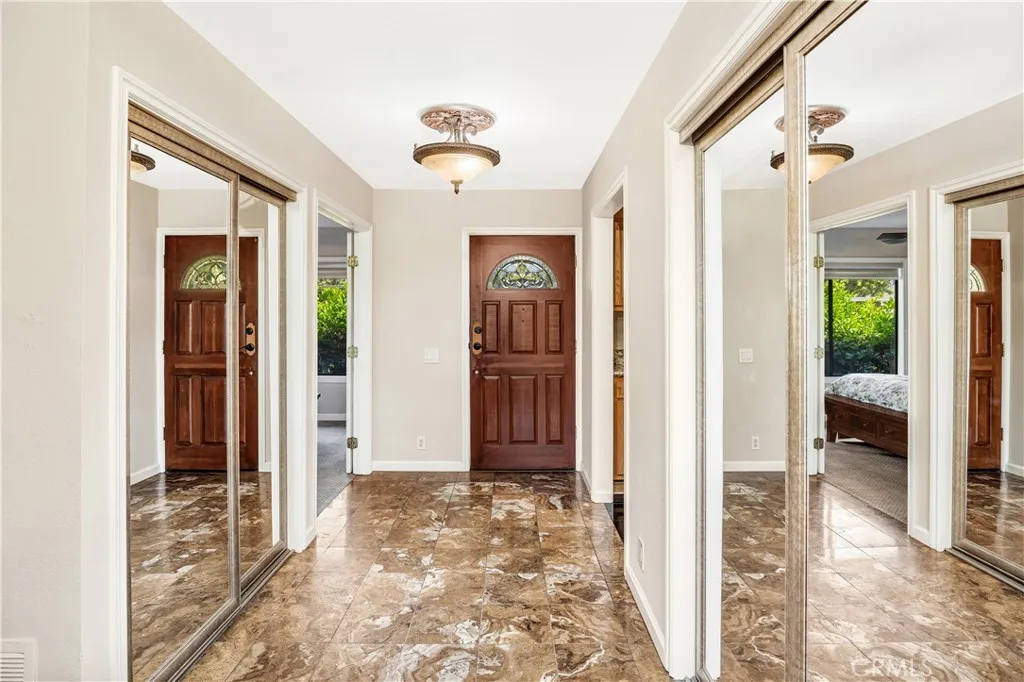 The view of the front door and entry, two closets are flanking the tiled hallway. The second bedroom is to the left and the kitchen is to the right.