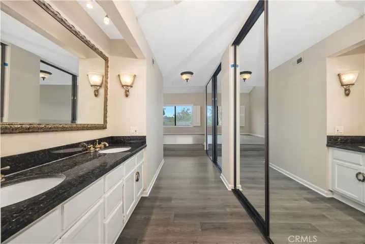 New flooring for primary bathroom. Granite countertop with dual vanities and elegant mirror.