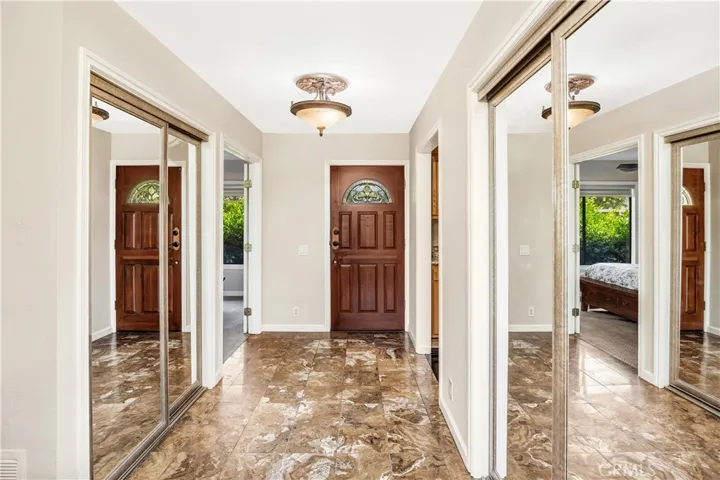 The view of the front door and entry, two closets are flanking the tiled hallway. The second bedroom is to the left and the kitchen is to the right.