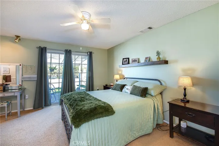 Elegant master bedroom with ceiling fan and slider to a private covered patio.