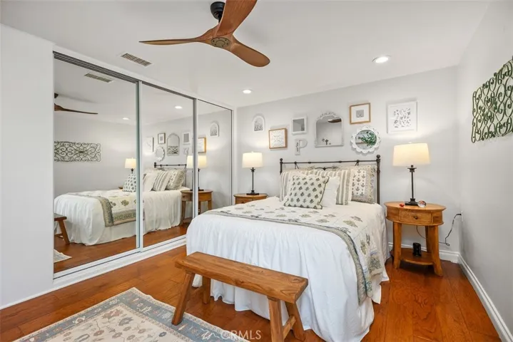 Primary bedroom with mirrored wardrobe doors, recessed lighting and ceiling fan.