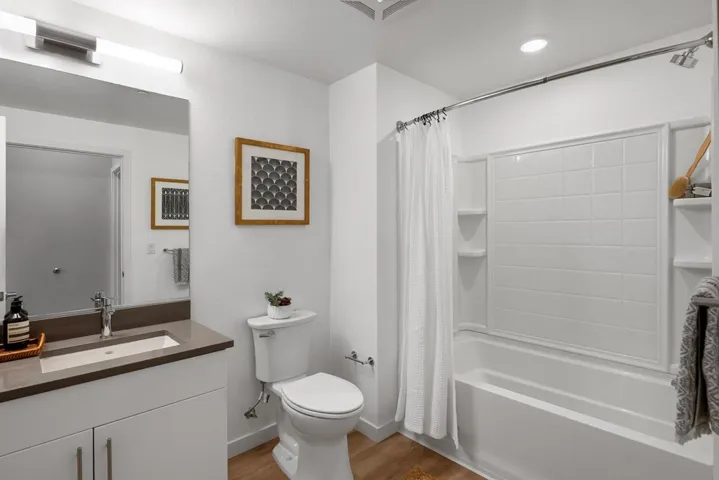 Bathroom featuring shower / bath combination with curtain, light wood finished floors, vanity, and recessed lighting