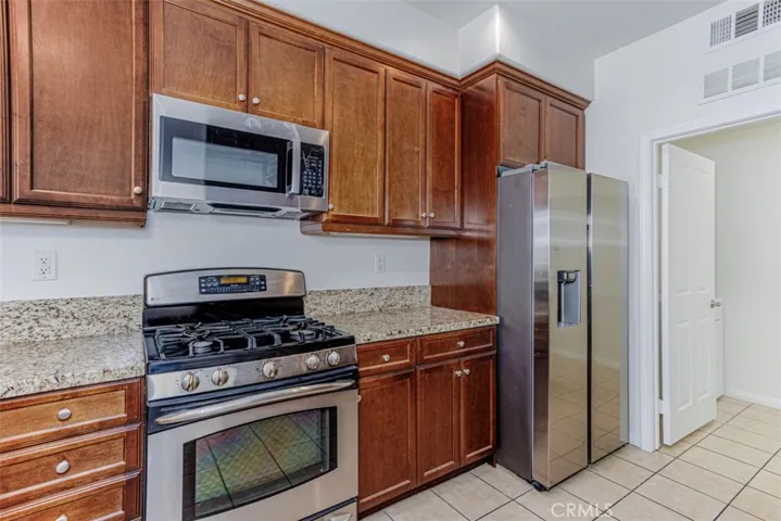Gourmet kitchen with granite countertops, stainless steel appliances, including refrigerator.