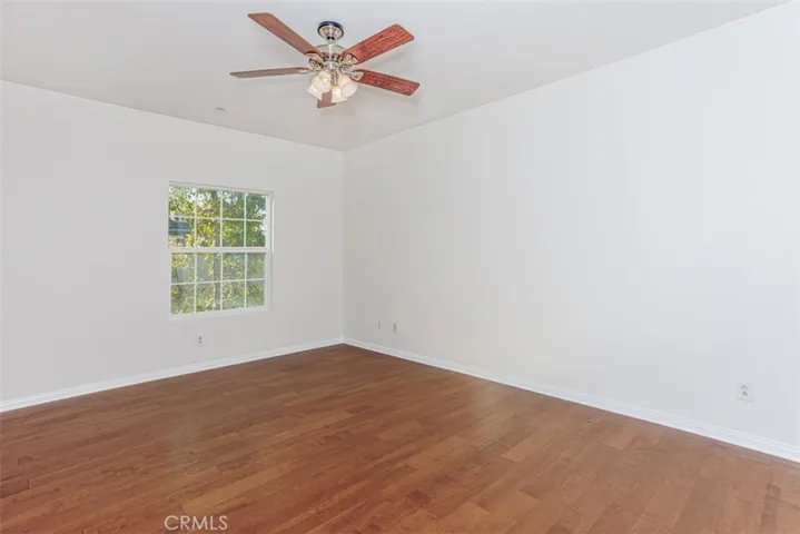 Primary bedroom with hardwood floors and ceiling fan.